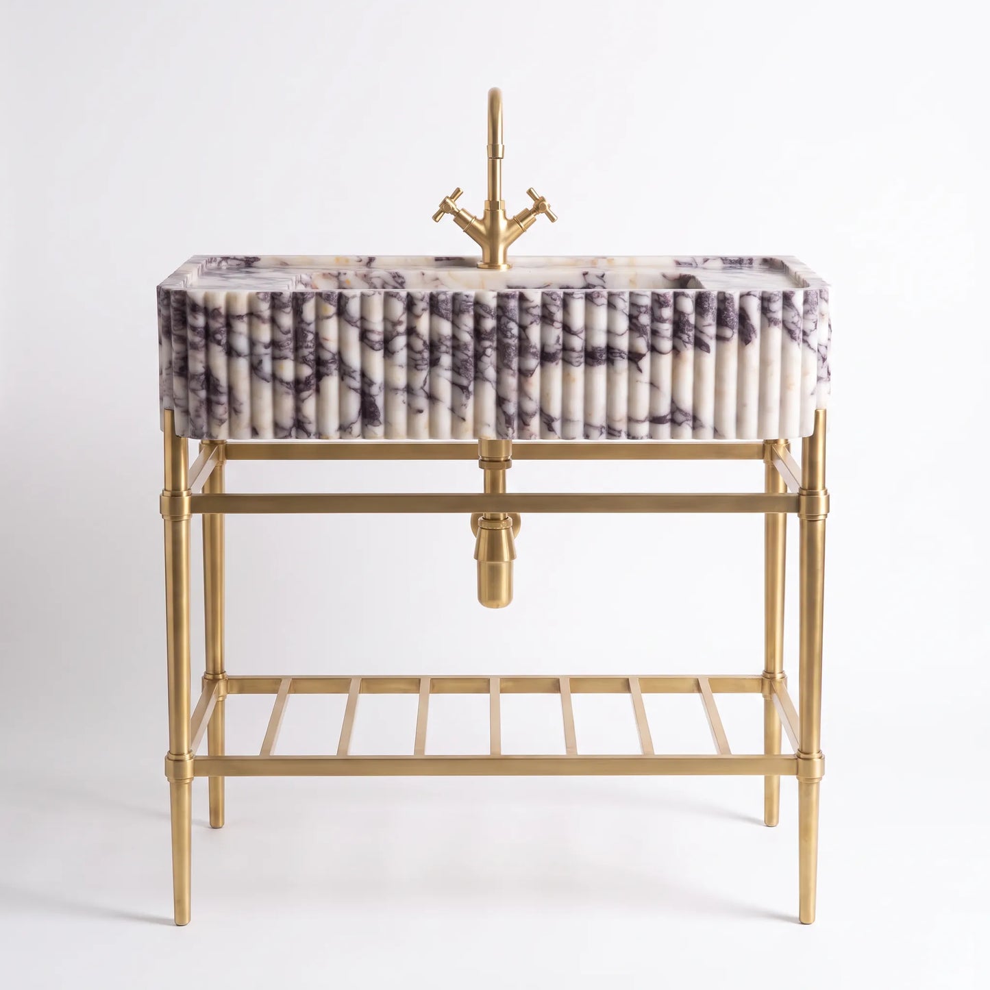 A modern bathroom vanity featuring a rectangular marble sink with a purple and white veined pattern, mounted on a gold-finished metal frame with a matching gold faucet and a lower shelf.