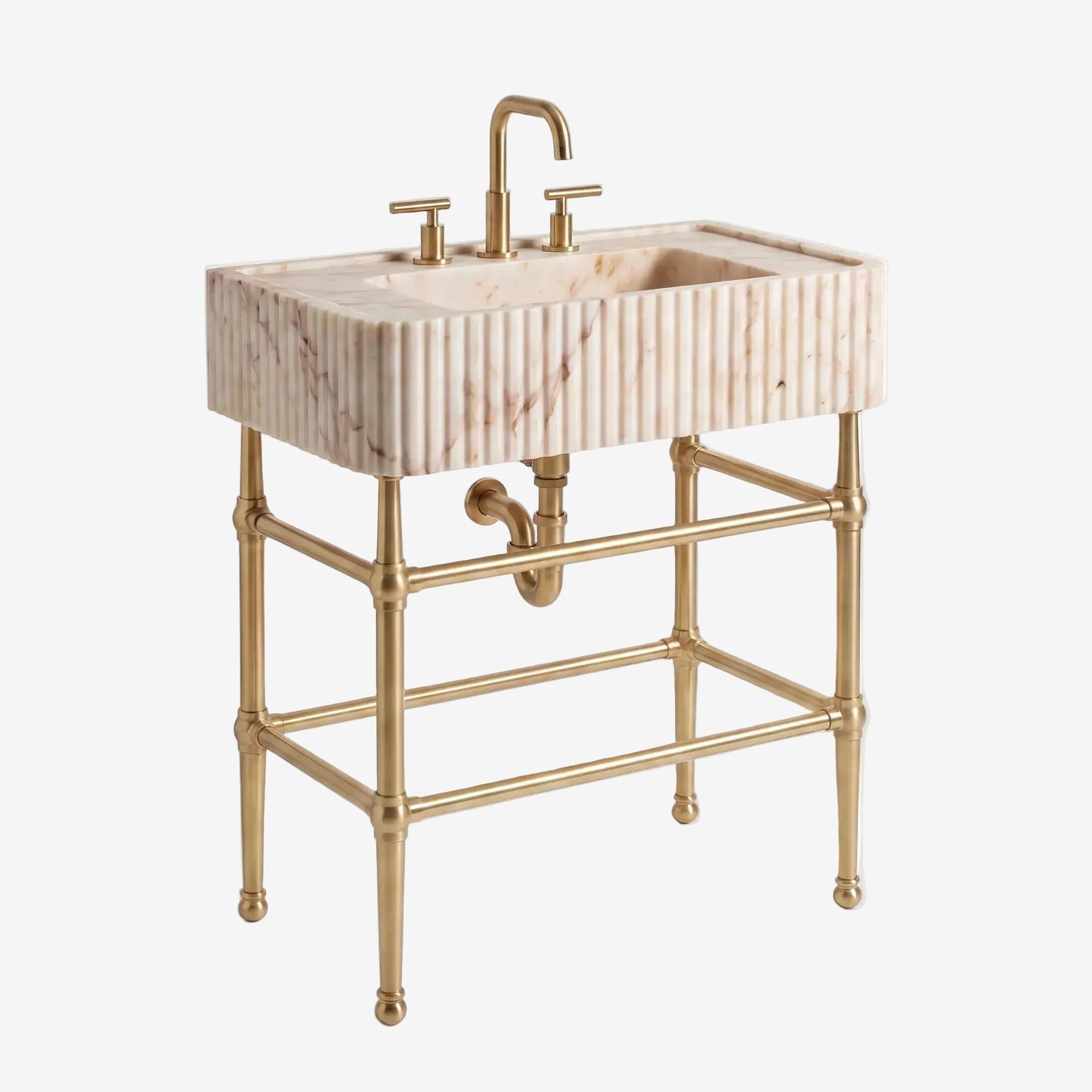 A freestanding bathroom vanity with a rectangular marble sink featuring vertical fluting, a curved brass faucet, and a matching brass double-handle faucet and support frame, shown on a light gray studio background.