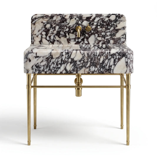 A modern vanity sink with a black and white marble patterned basin and backrest, supported by a polished gold brass frame with a central drain and two faucet handles.