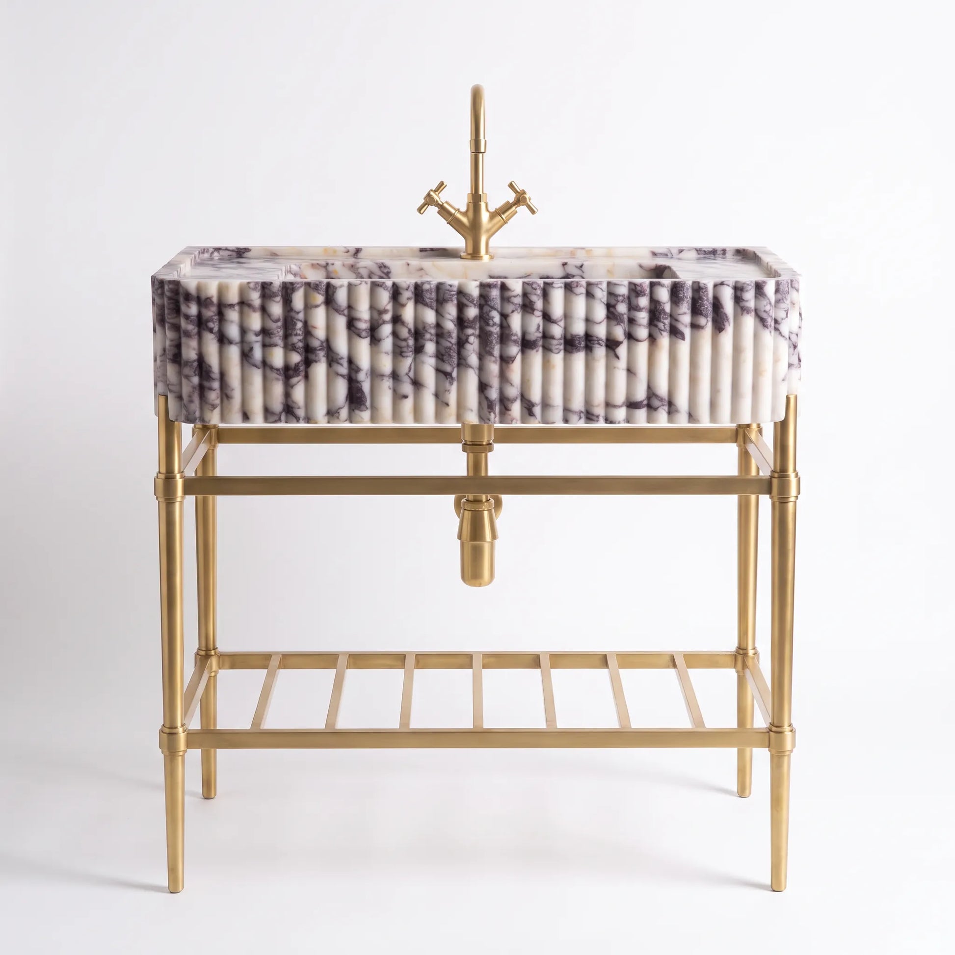 A modern bathroom vanity featuring a rectangular marble sink with a purple and white veined pattern, mounted on a gold-finished metal frame with a matching gold faucet and a lower shelf.
