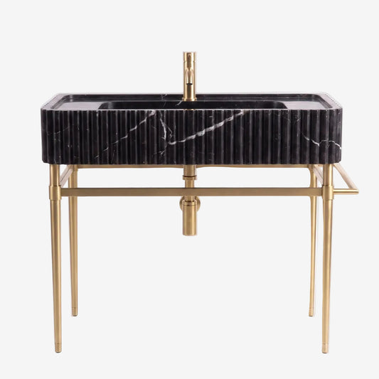 A modern rectangular bathroom vanity with a black marble sink top featuring white veining, supported by a gold-finished metal frame with slim legs and a matching gold faucet.