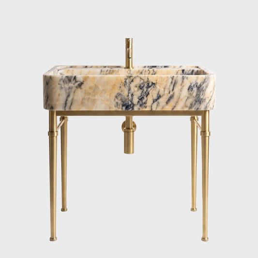 A modern rectangular vessel sink with a beige and black marble pattern, supported by a gold-finished metal stand with four legs and a matching gold faucet, set against a plain white background.