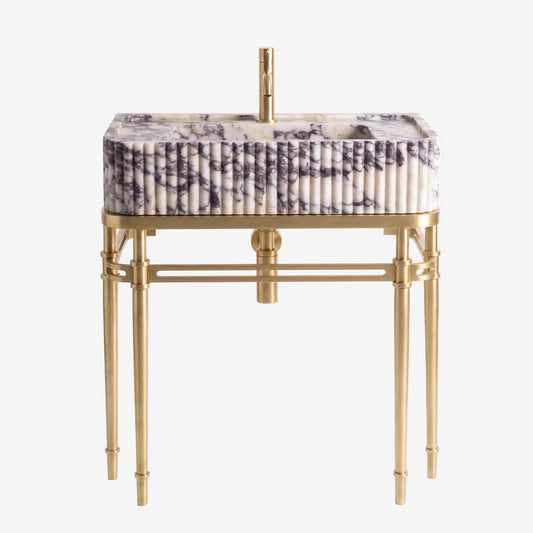 A modern rectangular bathroom vanity with a fluted marble basin featuring white, gray, and purple veining, supported by a polished gold brass frame with elegant legs and a matching gold faucet.