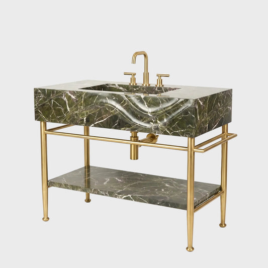 A modern bathroom vanity featuring a rectangular green marble sink with dramatic white veining, supported by a gold-finished metal frame with an open lower shelf and integrated faucet.