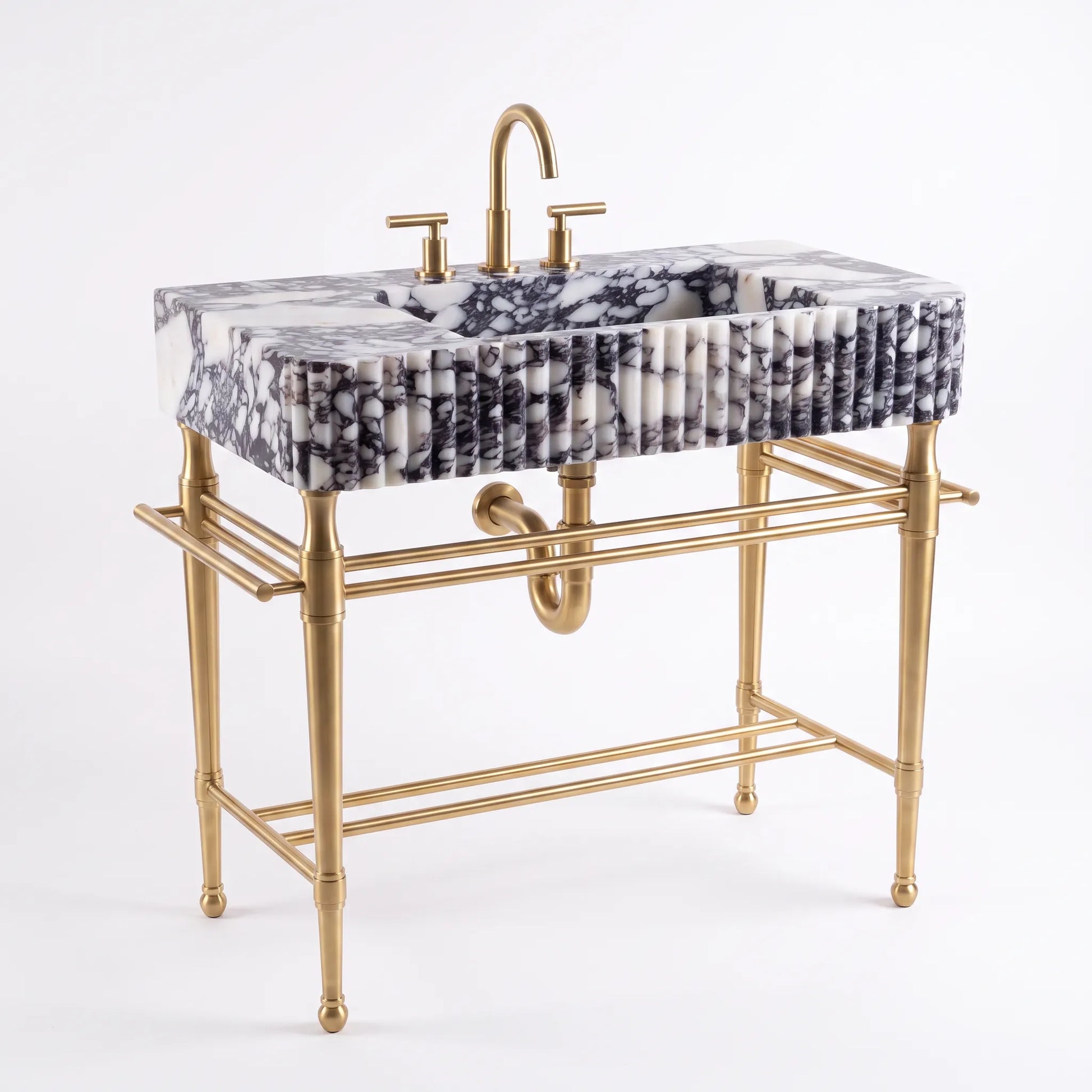 A modern bathroom vanity featuring a rectangular white and black marble sink with a fluted front, supported by a gold-finished metal stand with a matching curved faucet and two-hole lever handles.